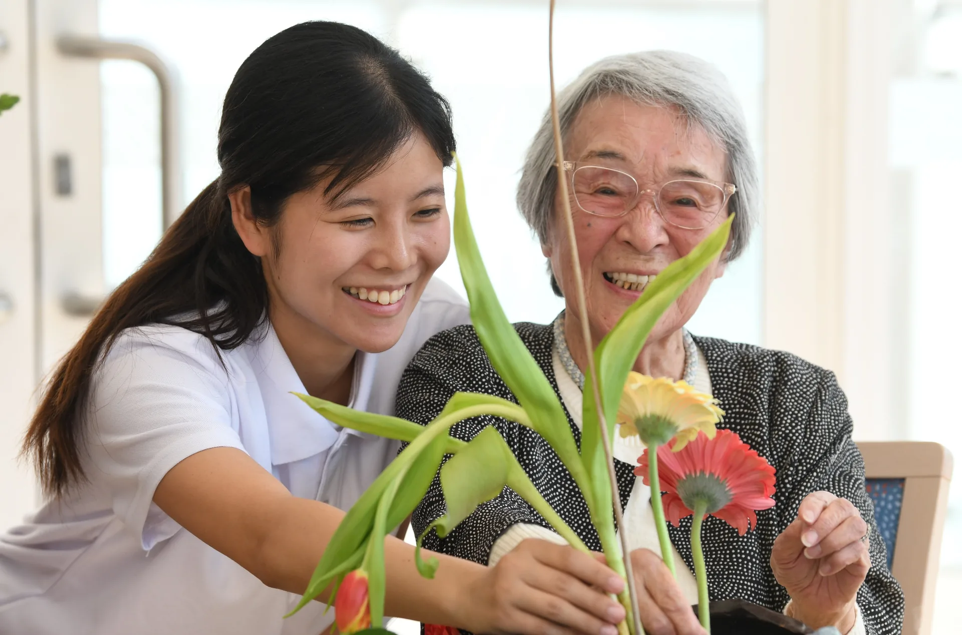Carer helping a resident with flower arranging at Dougherty Apartments.