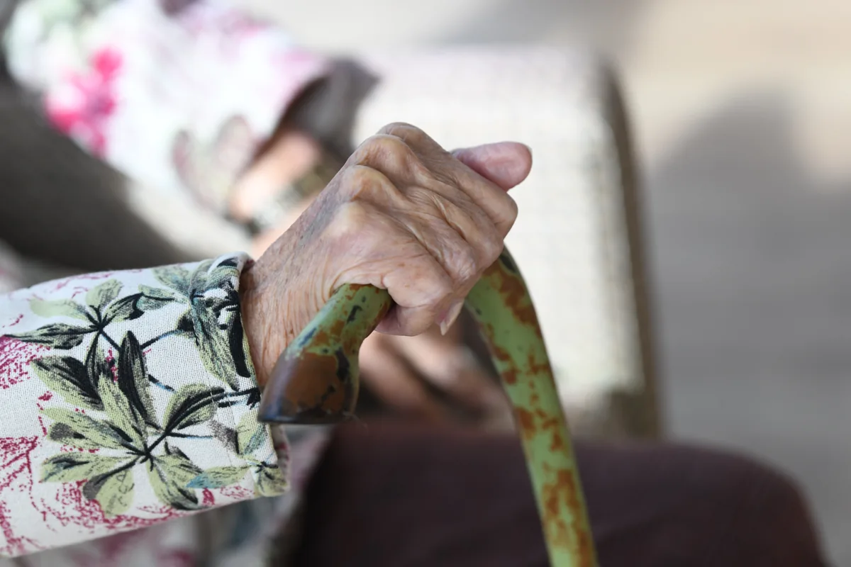 A resident’s hand holding a walking stick